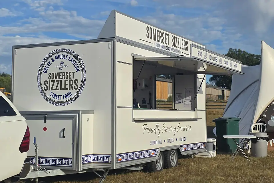 The trailer with its hatch open in a field beside a marquee, ready to serve party guests