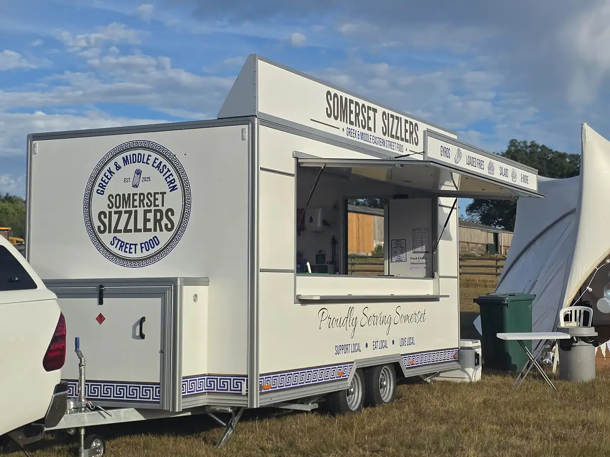 The Somerset Sizzlers trailer open for service in a field beside a white marquee